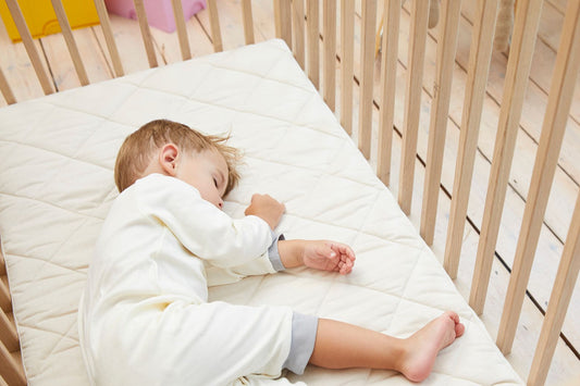 A picture of a baby sleeping on a natural nursery mattress.